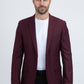 Man wearing a burgundy blazer over a white shirt on a white background