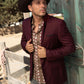 Man wearing a burgundy blazer and cowboy hat standing next to a wooden fence.