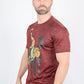 A man wearing a heathered red short-sleeve t-shirt with a cowboy riding a black horse graphic on the front, paired with blue jeans, photographed against a light gray background.